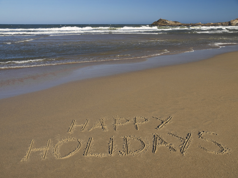 Happy Holidays written in sand at the beach